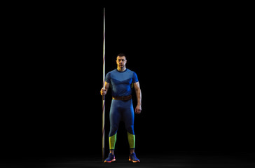 Male athlete practicing in throwing javelin on black background in neon light. Professional sportsman posing confident. Concept of healthy lifestyle, movement, activity, competition. Copyspace.