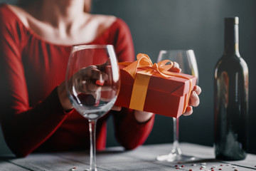 Congratulation concept for valentines day. couple at the table in a restaurant. dim lights, lovers give each other gifts.
