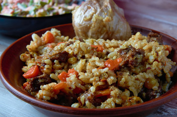 Uzbek national plov dish on a clay plate closeup.