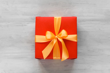 red box tied with a gold ribbon. the ribbon is tied on a box in the form of a beautiful bow. holiday gift concept