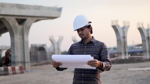 Slow motion Asian engineers worker and looking into the blueprints at construction site