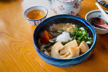 Winter udon with hot tea on wood table.