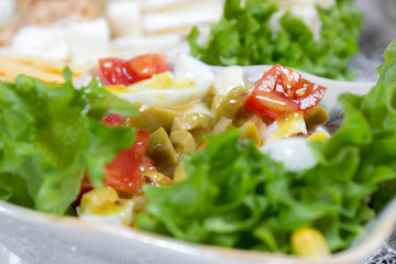Greek salad with olives, tomatoes, feta cheese, onions in blue bowl on wooden background. Close up. Selective focus.