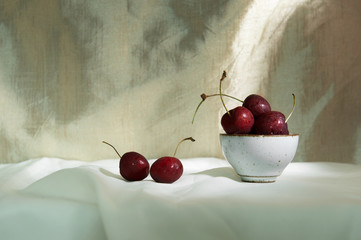 still life of red purple cherry fruit for food in ceramic bowl with golden fabric vintage background