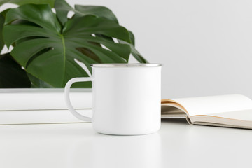 Enamel mug mockup with workspace accessories and a monstera plant.