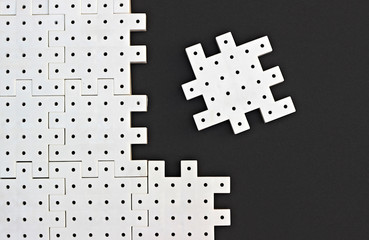 White puzzle pieces on the black background show cohesion, teamwork and agreement.