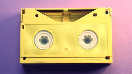 Yellow video tape on purple background, VHS, 90s concept, videotape, cassette