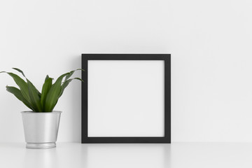 Black square frame mockup with a dracaena in a pot on a white table.