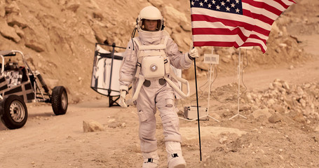 Astronaut with american flag standing on the Rocky Mountain of the Alien Red Planet/ Mars. First Manned Mission on Mars - Powered by Adobe