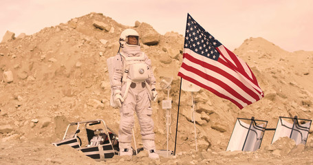 Astronaut with american flag standing on the Rocky Mountain of the Alien Red Planet/ Mars. First Manned Mission on Mars