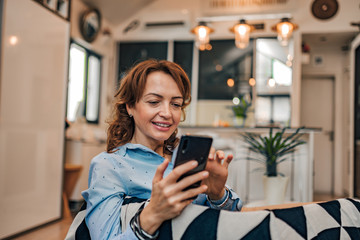 Home portrait of a woman relaxing and using smart phone, copy space.