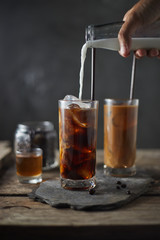 Ice coffee in a tall glass on wooden table..