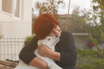 Mature woman embracing pet dog in nature