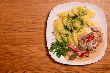 Beef meat stewed with potatoes, carrots and spices in ceramic pot on wooden background