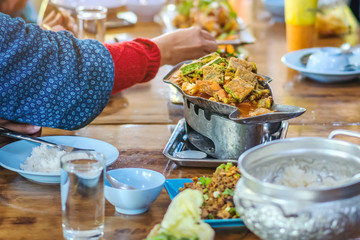 Group of female friends enjoy eating with acacia pennata omelette sour soup in fish shape hot pot in the restaurant. Selective focus.