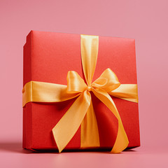 red gift box tied with a golden ribbon. Ribbon tied with a bow on a box. gift concept
