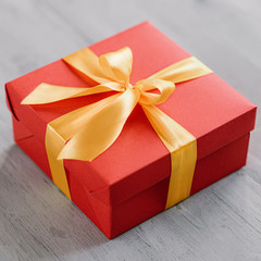 red gift box tied with a golden ribbon. Ribbon tied with a bow on a box. gift concept