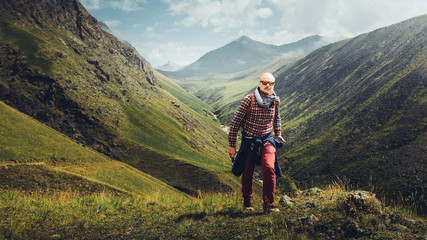 Fototapeta na wymiar Adventure Blogger Travel Concept. Handsome Male Traveler Hiking On The Hills