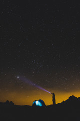 Standing man with torch light looking the black space night galaxy and enjoy th eoutdoor leisure activity in alternative cemping vacation travel