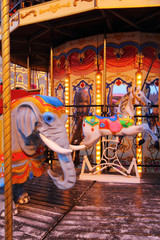 Fototapeta na wymiar Christmas Marry-Go-Round Carousel with horses and elephant. Garland lights on.