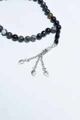 Handmade rosary necklace made of beads, black agate and silver on white Background	
