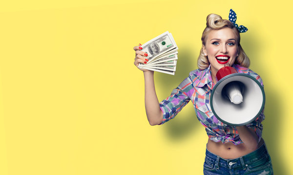 Portrait picture of beautiful pinup girl. Happy excited woman holding cash money banknotes and megaphone, pinup style. Retro fashion and vintage concept. Yellow color background. Copy space.