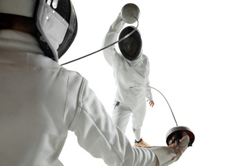 Teen girls in fencing costumes with swords in hands isolated on white studio background. Young...