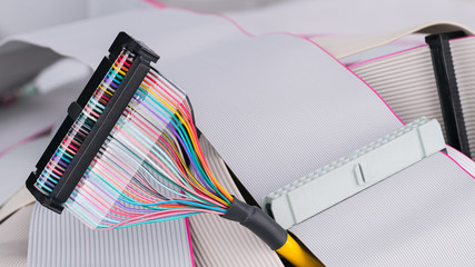 Colorful multi wire bus connector on white ribbon cables background. Internal integrated drive...