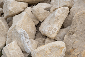 Big pile of large sand stones laying on the ground of construction site.