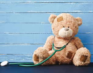 teddy bear is sitting, green stethoscope is hanging on his neck
