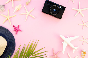 Fototapeta na wymiar Top view female travel blogger frame mockup with copy space. Palm leaf, plane, vintage camera and straw hat on a pink background