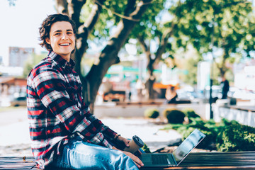 Young man sitting on the park bench with laptop