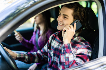 Young couple travelling by car while man talking by phone