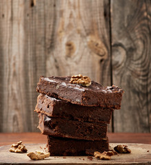stack of square baked slices of brownie chocolate cake with walnuts