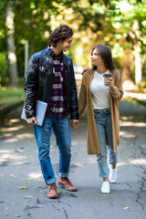 Obraz premium Photo of young loving couple students outdoors outside at street walking drinking coffee talking with each other.