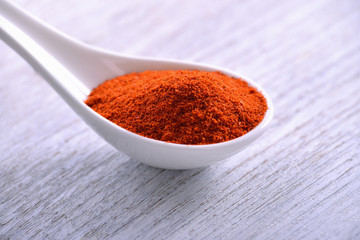 Paprika powder in white spoon on table