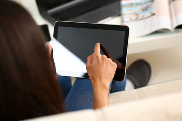 female hand holds tablet in home setting while