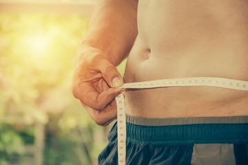 man using measuring tape on body.Health and wellness concept.Body of sexy man after exercise.Closeup of fit young man body.
