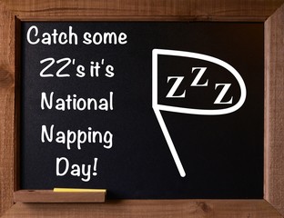 Photo of a black chalkboard with a message for National Holiday, National Napping Day.