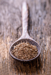Cumin seeds in spoon on wooden table
