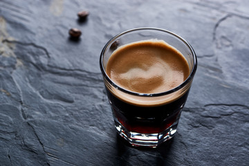 Coffee in glass cup on dark stone background. Close up.