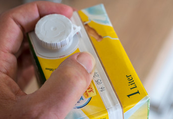 Hand √∂ffnet 1-Liter Milcht√ºte - mit sichtbarem Mindesthaltbarkeitsdatum