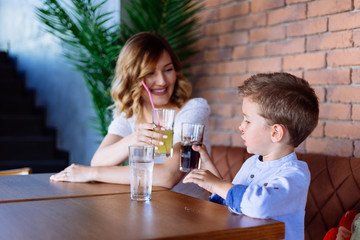 Cute boy toasting with his mom with soda soft drink. Unhealthy children habits