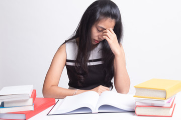 Exhausted Asian woman got headache read a book with books on table.