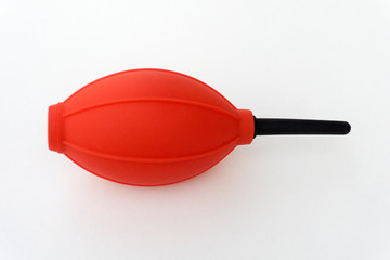 Red and black camera air blower for clearing dust particles from lens.