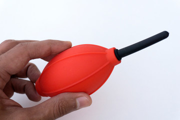 Red and black camera air blower for clearing dust particles from lens.