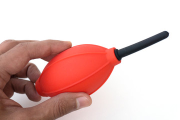 Red and black camera air blower for clearing dust particles from lens.
