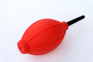 Red and black camera air blower for clearing dust particles from lens.