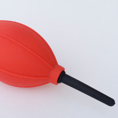 Red and black camera air blower for clearing dust particles from lens.