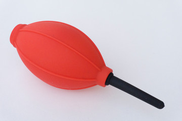 Red and black camera air blower for clearing dust particles from lens.